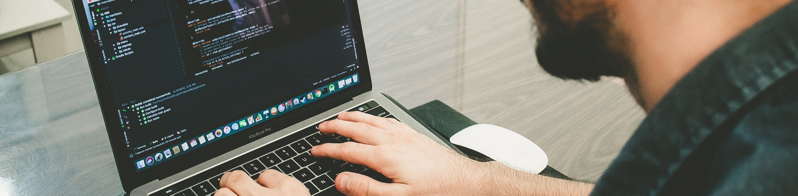A picture of a man writing code on his laptop.